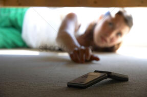 A woman trying to get a hand phone from under the bed Stock Photo - 1679336 | StockUnlimited