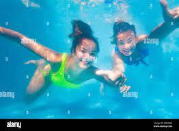 Two happy teenage girls swim playing together underwater in the pool waving hands showing cheerful hand gestures Stock Photo - Alamy