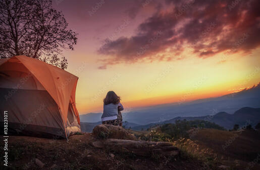 Woman sitting on a mountain watching the sunset.she is camping alone. Stock Photo | Adobe Stock