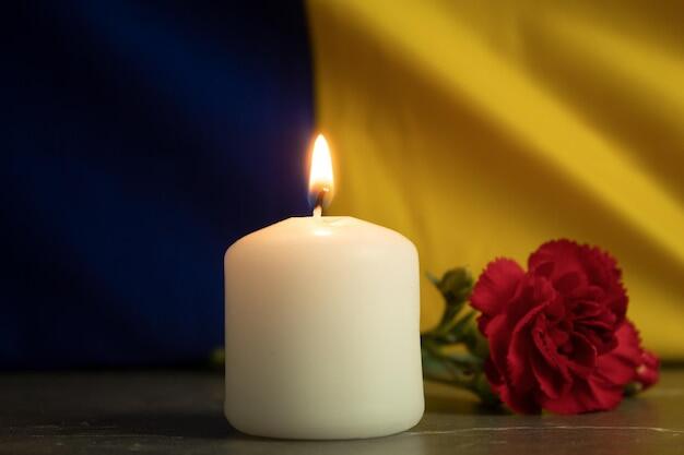 Фото однієї палаючої свічки на тлі державного прапора україни