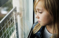 Portrait of a 9 year old sad girl who is sitting next to a window Photos | Adobe Stock