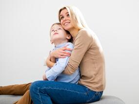 Front view blonde mother hugging her son